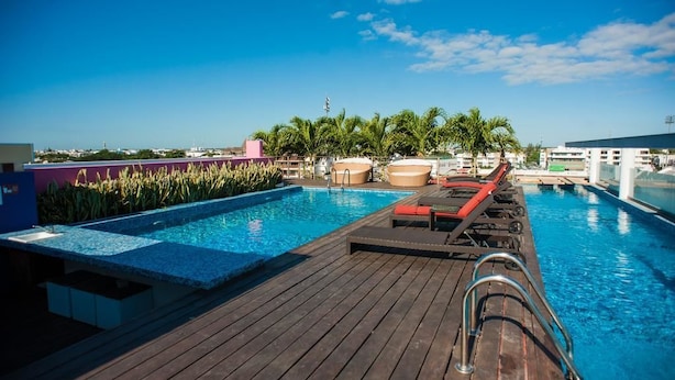A wooden deck with a pool, lounge chairs, and palm trees. - Sabbia 301 by Tripintravel (Playa del Carmen)