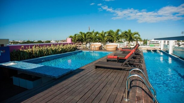 A wooden deck with a pool, lounge chairs, and palm trees. - Sabbia 310 by Tripintravel (Playa del Carmen)