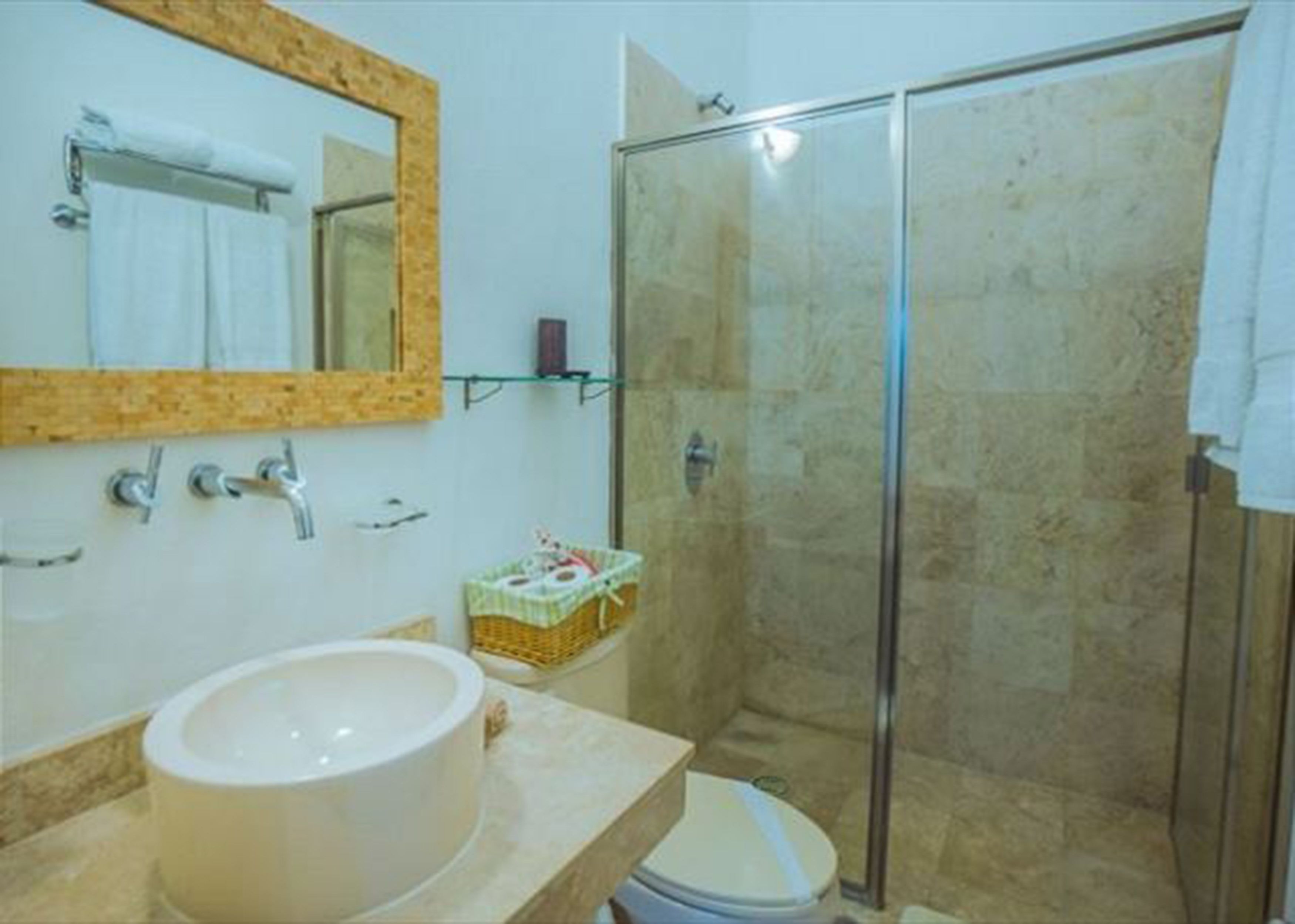 Une salle de bain avec un grand miroir, un lavabo, des toilettes et une douche à parois de verre.