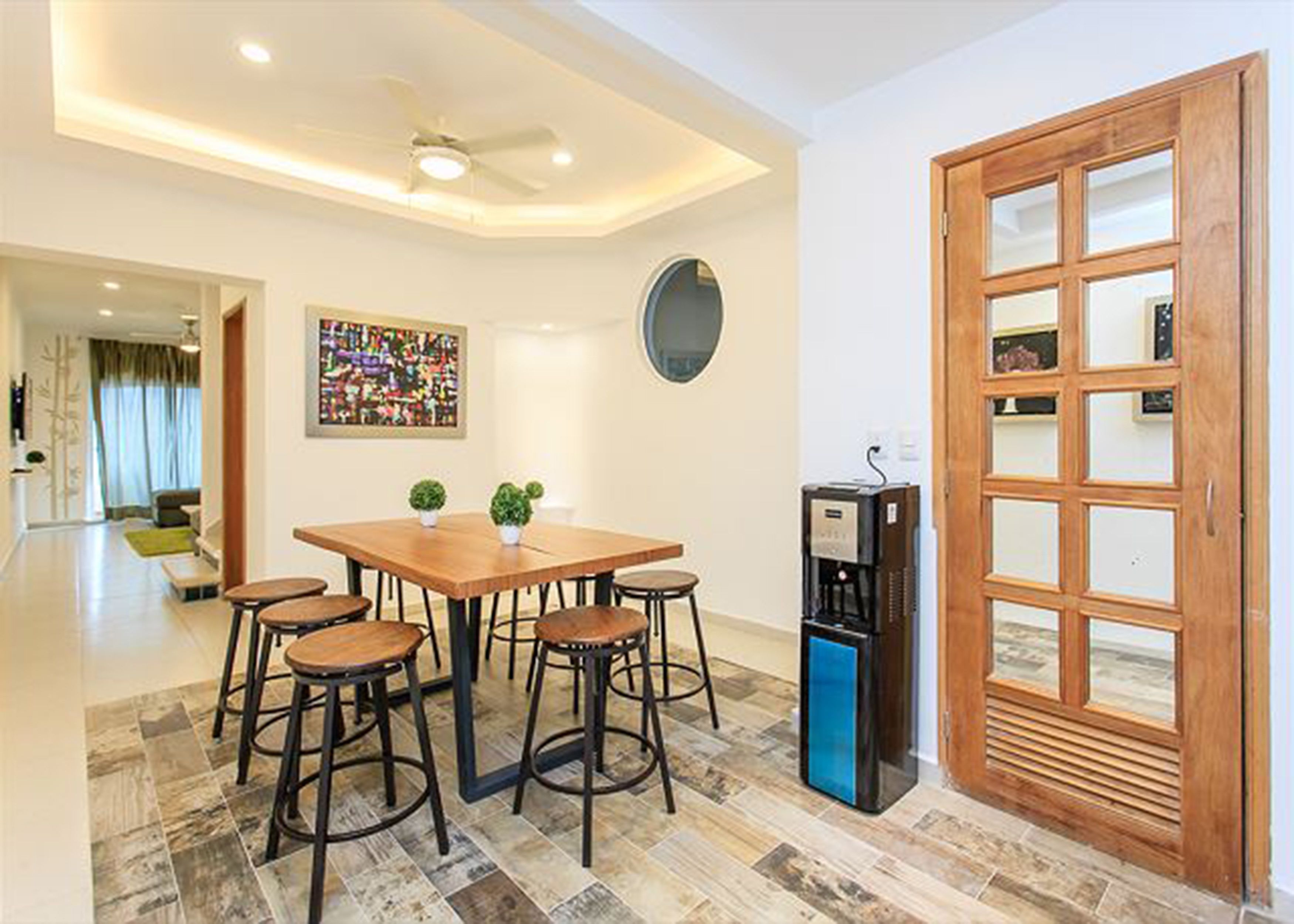 A dining area with a wooden table, four stools, a coffee machine, and a decorative mirror.