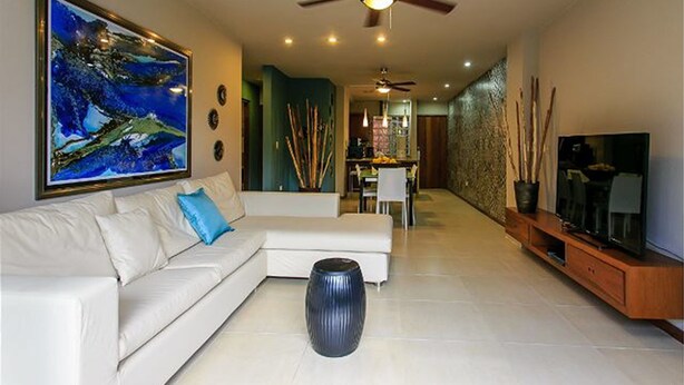 A modern living room with a white sofa, a large abstract painting, a ceiling fan, and a TV on a wooden stand. - Nolita 24 by Tripintravel (Playa del Carmen)