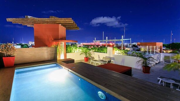 A rooftop pool area with a wooden deck, lounge chairs, and potted plants. - Nolita 34 by Tripintravel (Playa del Carmen)