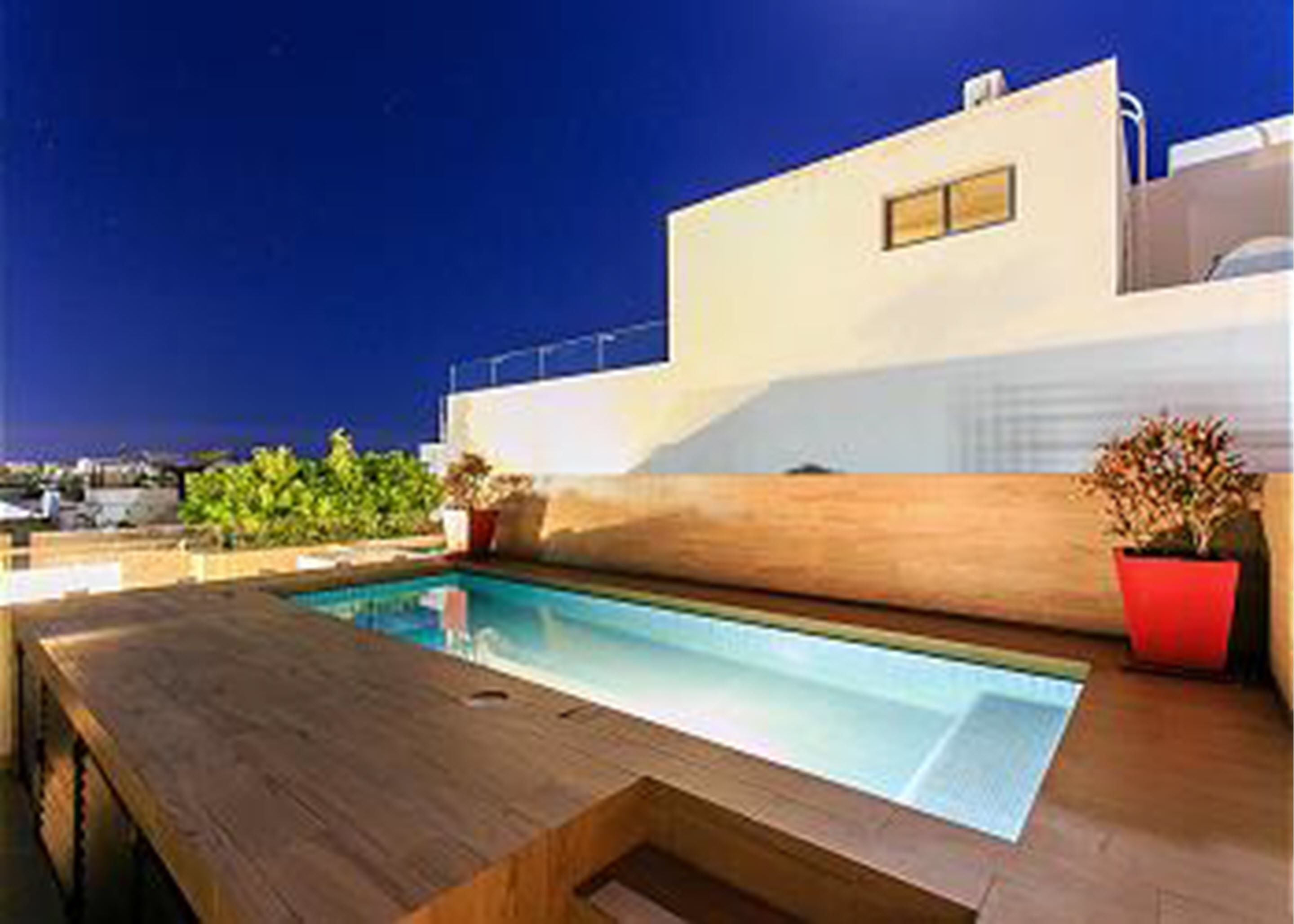 A modern pool area with a wooden deck and a white building in the background. - Nolita 12 by Tripintravel (Playa del Carmen)