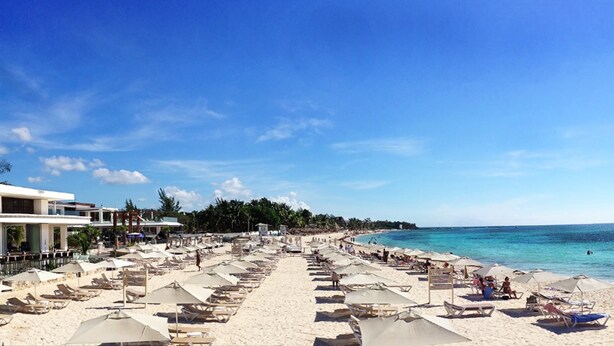 A beach resort with rows of sun loungers and umbrellas, a clear blue sky, and a calm sea. - Nolita 33 by Tripintravel (Playa del Carmen)