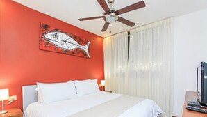 A hotel room with a bed, a ceiling fan, a painting of a fish, and a television on a wooden table. - Nolita 22 by Tripintravel (Playa del Carmen)