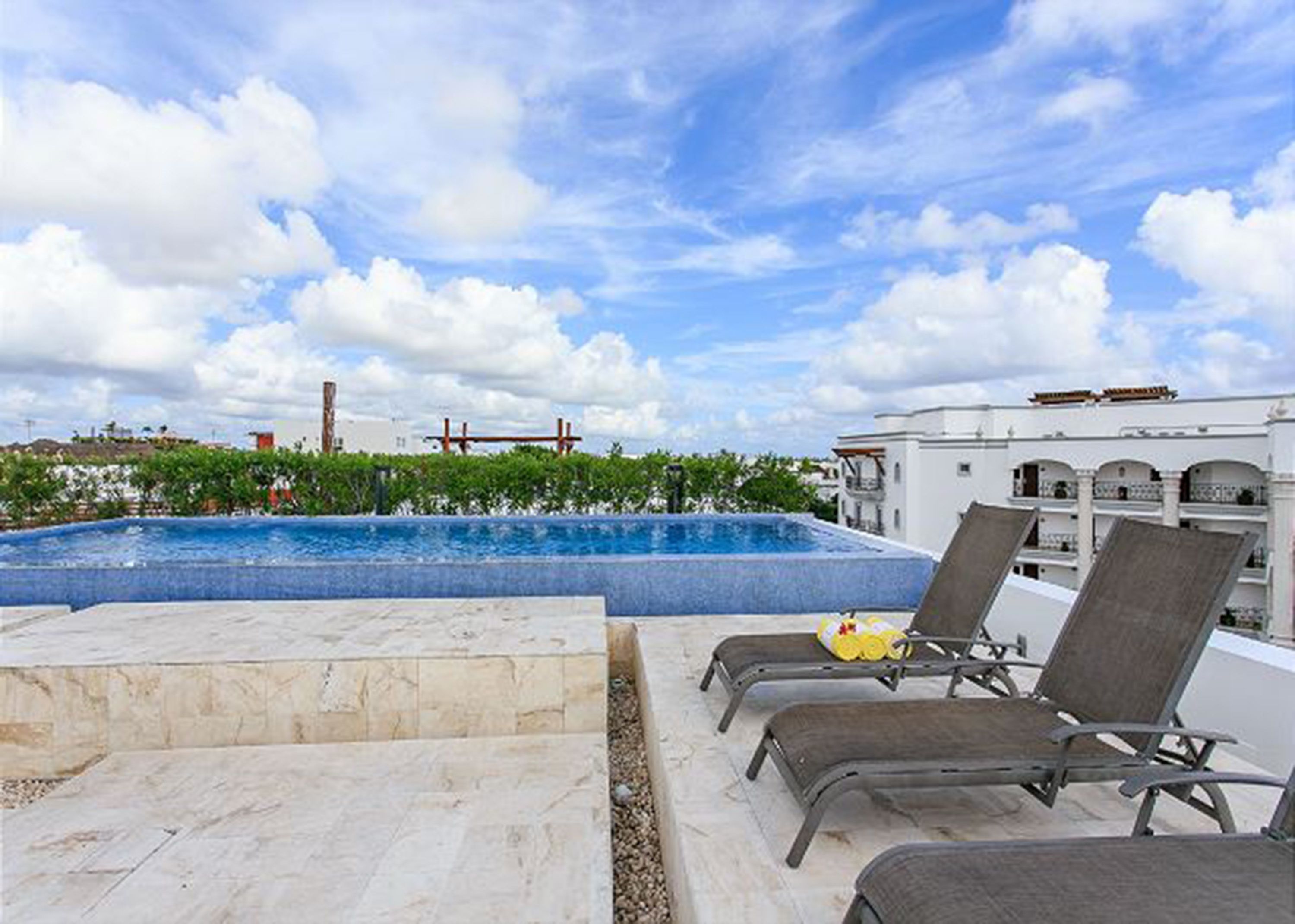 A rooftop pool area with lounge chairs and a clear view of the surrounding buildings.