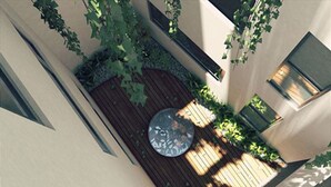 Ein Innenhof mit einer runden Sitzgruppe, umgeben von einer Holzterrasse und viel Grün.