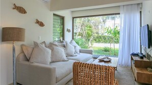 A modern living room with a sofa, a coffee table, and a TV. There are two wall-mounted fish decorations and a floor lamp. - Oceanfront Exclusive Home (Playa del Carmen)