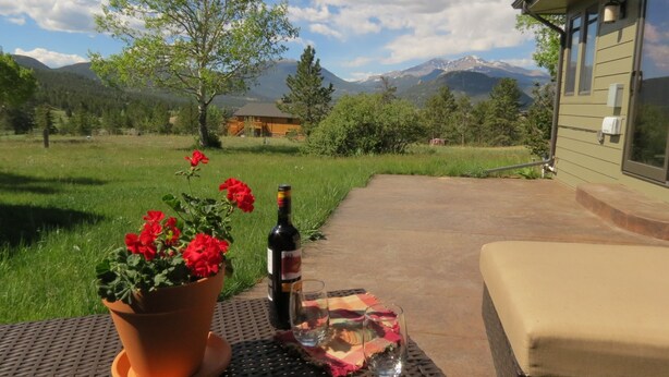 Un patio con una mesa lista para una comida, una botella de vino y un vaso de agua.