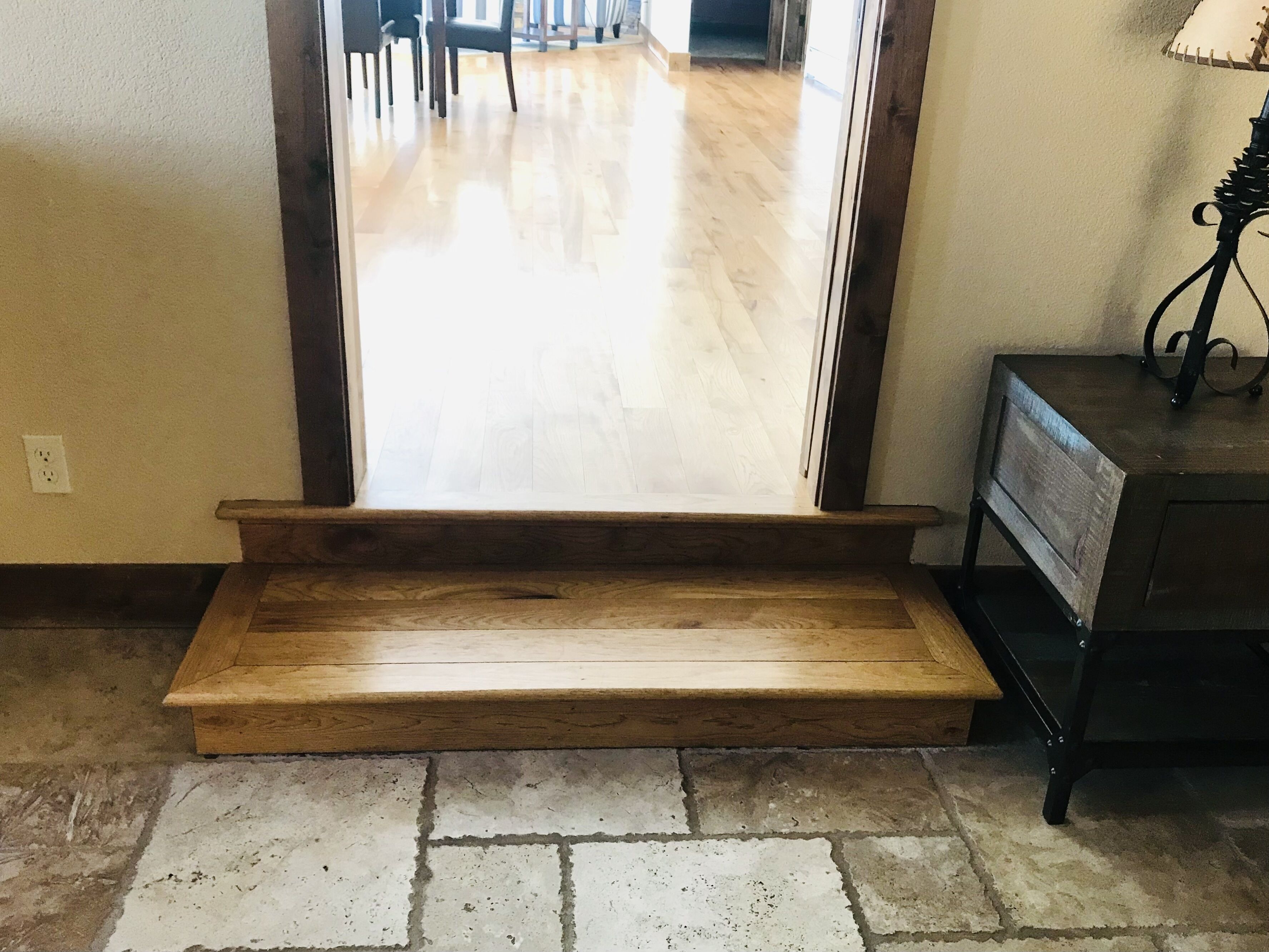 A wooden staircase leading to a room with a tiled floor and a dark wooden bench.