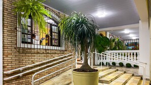 A staircase with a potted plant, white railings, and a brick wall with windows. - Parque Atlântico Hotel (Ubatuba)