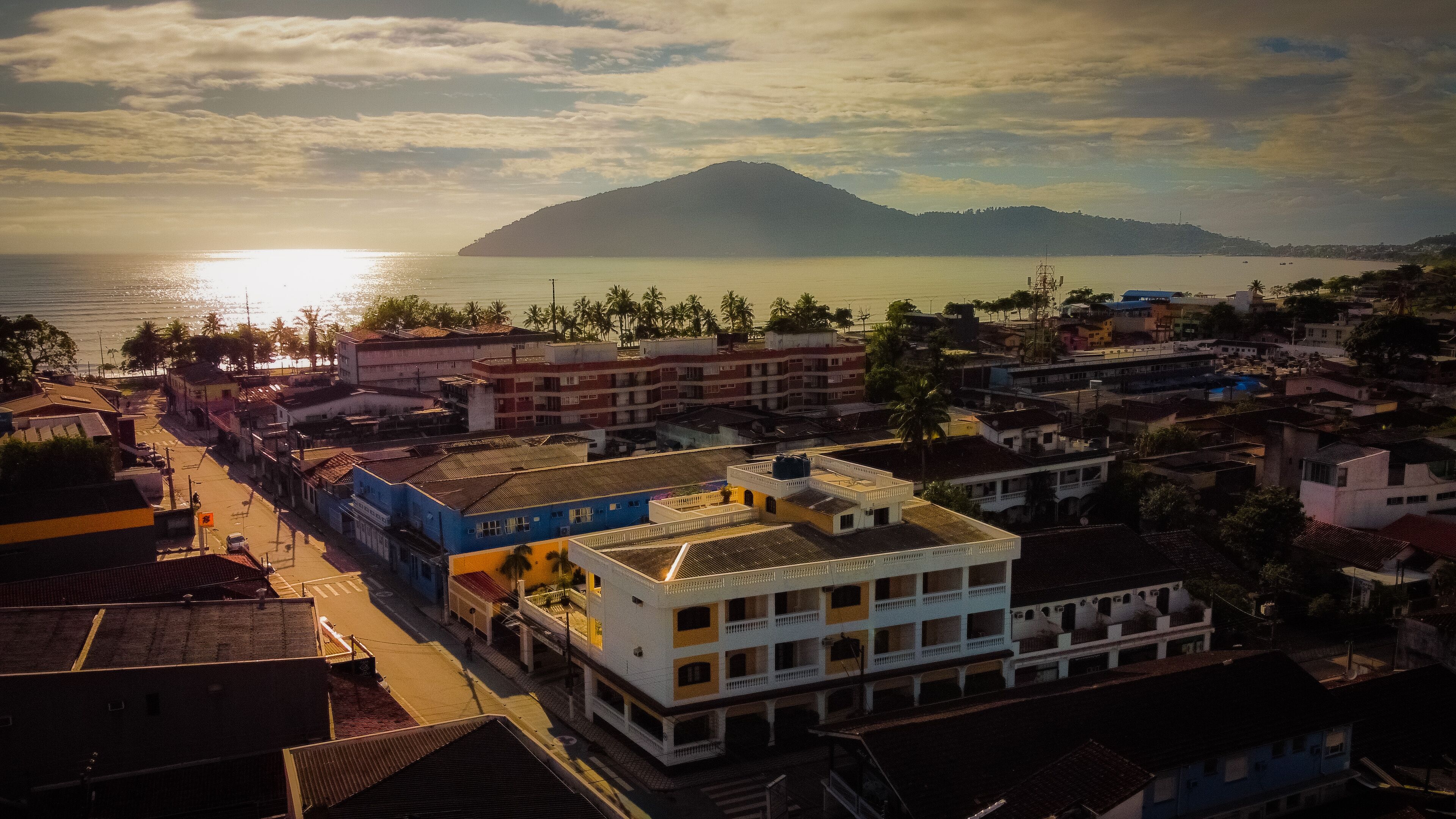 Uma cidade costeira com edifícios, uma rua e uma montanha ao fundo.