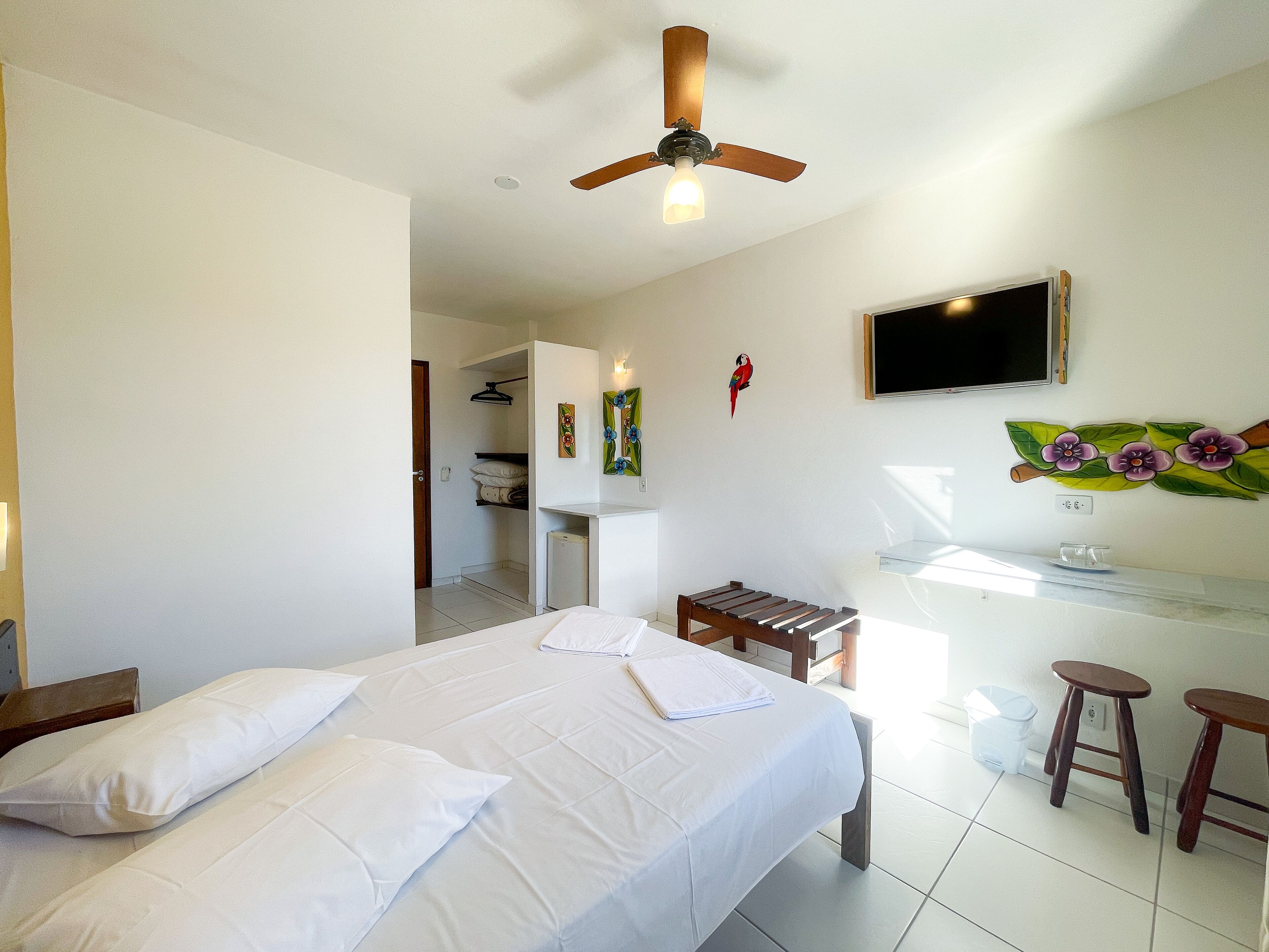 A hotel room with a bed, a desk, a chair, a TV, and a ceiling fan.