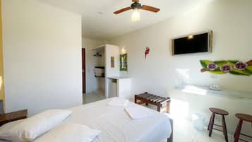 A hotel room with a bed, a desk, a chair, a TV, and a ceiling fan.