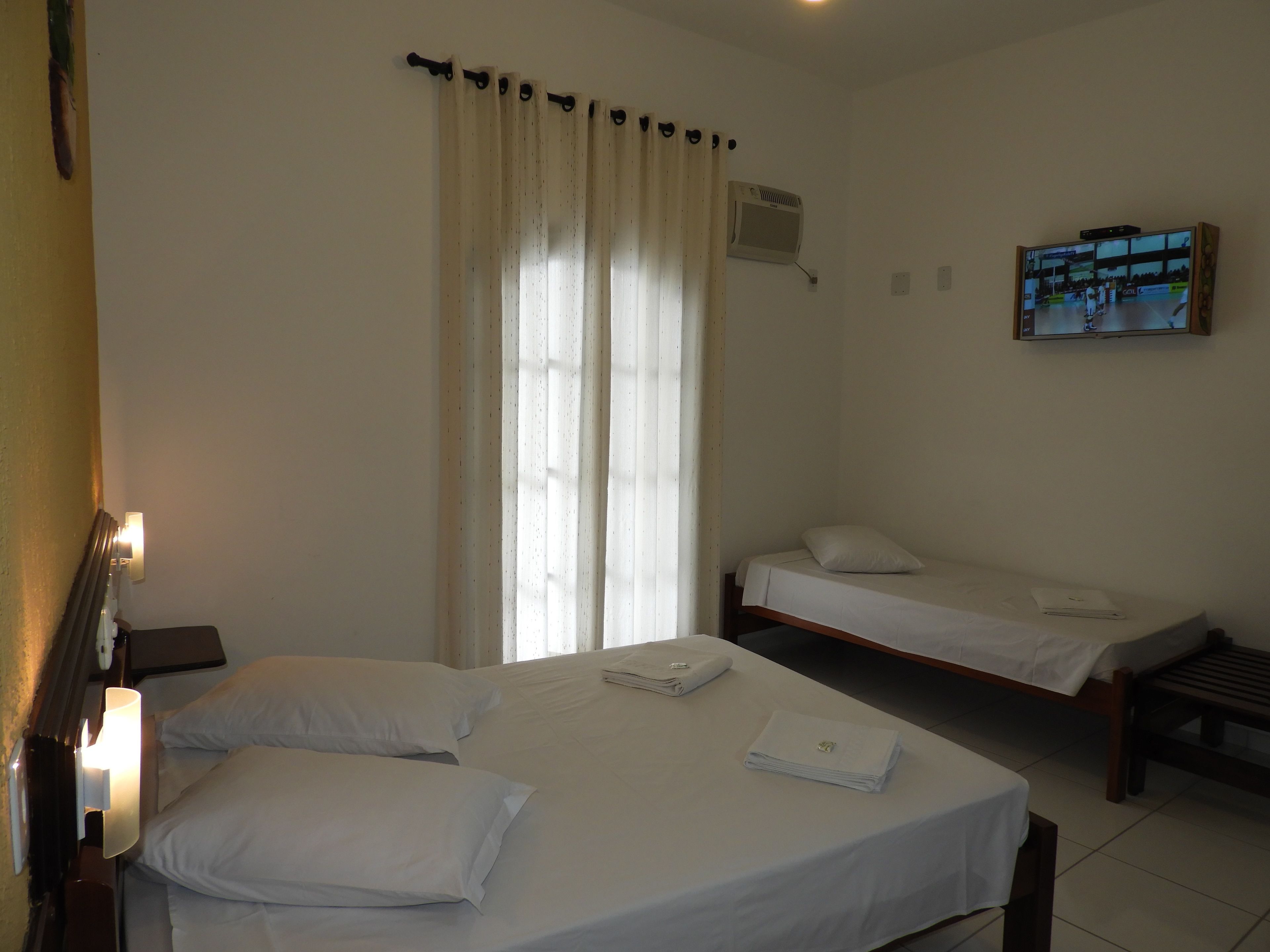 A hotel room with two beds, a TV, and a window with curtains.