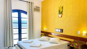 A hotel room with a bed, a nightstand, a wall-mounted air conditioner, a potted plant, and a window with curtains. - Parque Atlântico Hotel (Ubatuba)