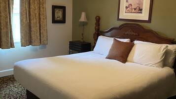 A neatly made bed with a wooden headboard, a ceiling fan, and a framed picture on the wall.