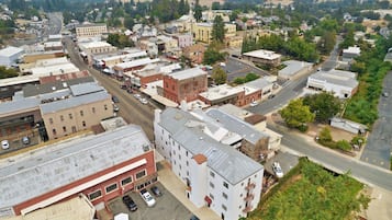 An aerial view of a town with a mix of commercial and residential buildings, a main street, and surrounding hills.