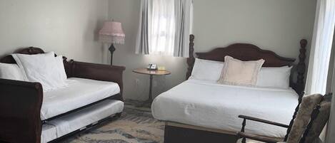 Une chambre d’hôtel avec un lit, un canapé, une petite table, un ventilateur de plafond et un tapis à motifs.
