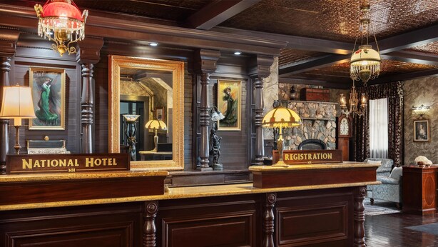 A reception desk with a sign reading "National Hotel NH" and a "Registration" sign. - National Hotel Jackson, Tapestry Collection by Hilton (Jackson)