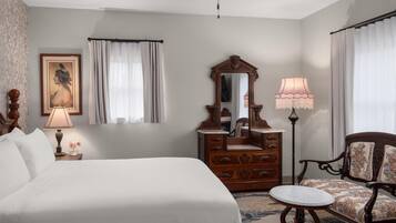 A hotel room with a bed, a dresser, a mirror, a chair, and a ceiling fan.