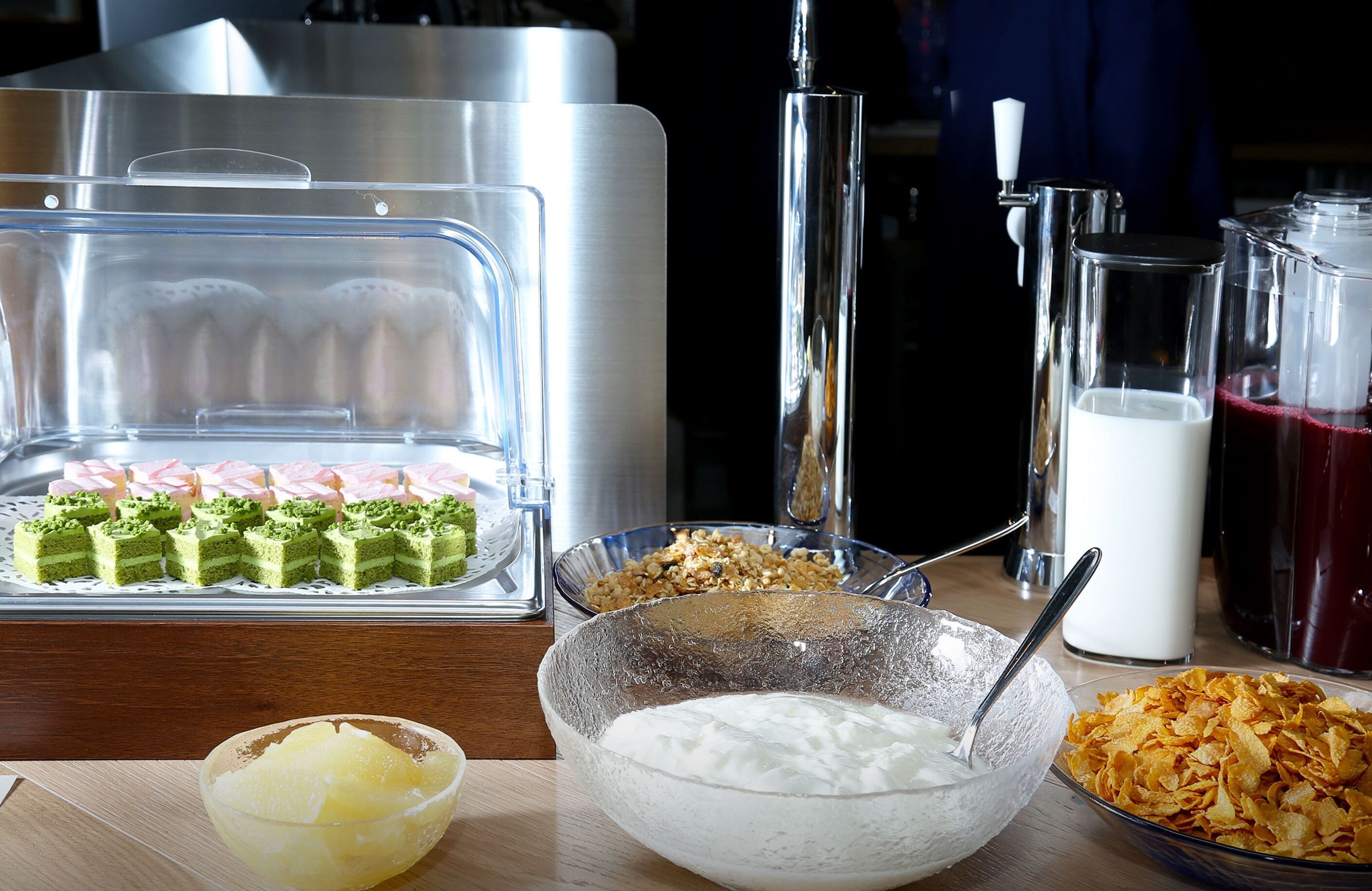 A buffet with various food items including cakes, yogurt, and cereal.
