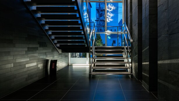 Uma escadaria moderna com guarda-corpos de vidro e vista da cidade através de amplas janelas.