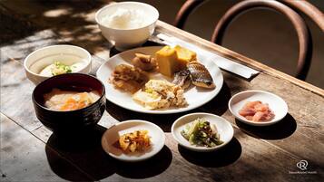 A wooden table with various dishes, including rice, fish, and vegetables, suggesting a meal setting.
