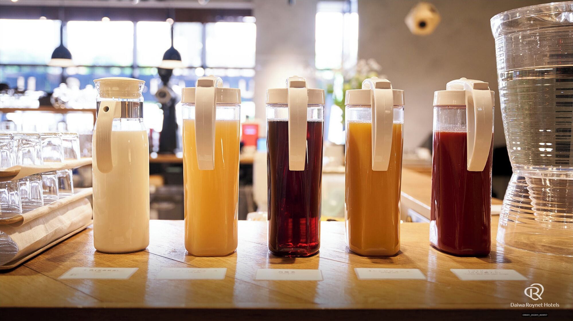 Uma área de bar com diversas bebidas em dispensadores e copos sobre o balcão.