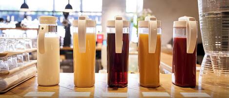 Uma área de bar com diversas bebidas em dispensadores e copos sobre o balcão.