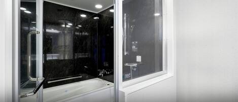 Un baño moderno con ducha envuelta en vidrio, bañera y retrete.