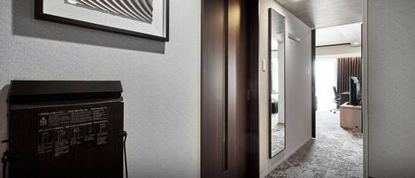 A hotel hallway with a dark wooden door, a framed artwork on the wall, and a carpeted floor.
