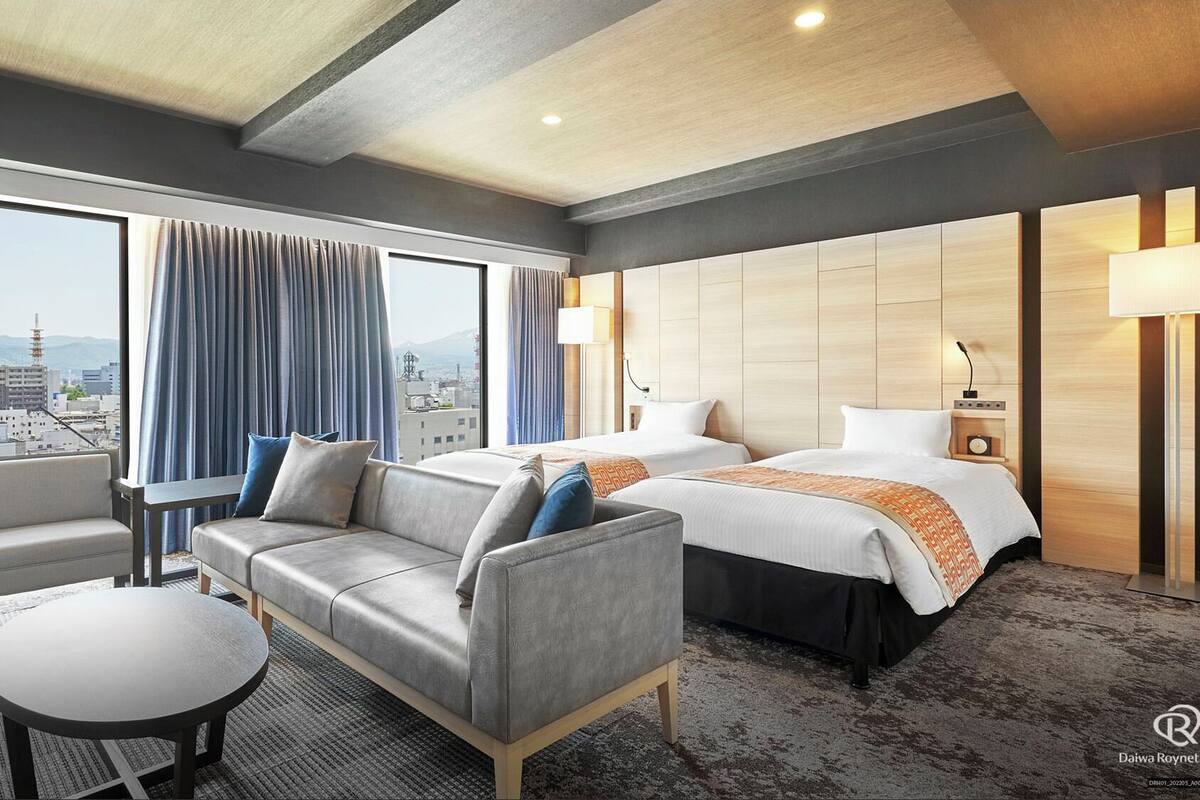 Hotelkamer met een bank, een bed, een bureau en uitzicht op de stad.