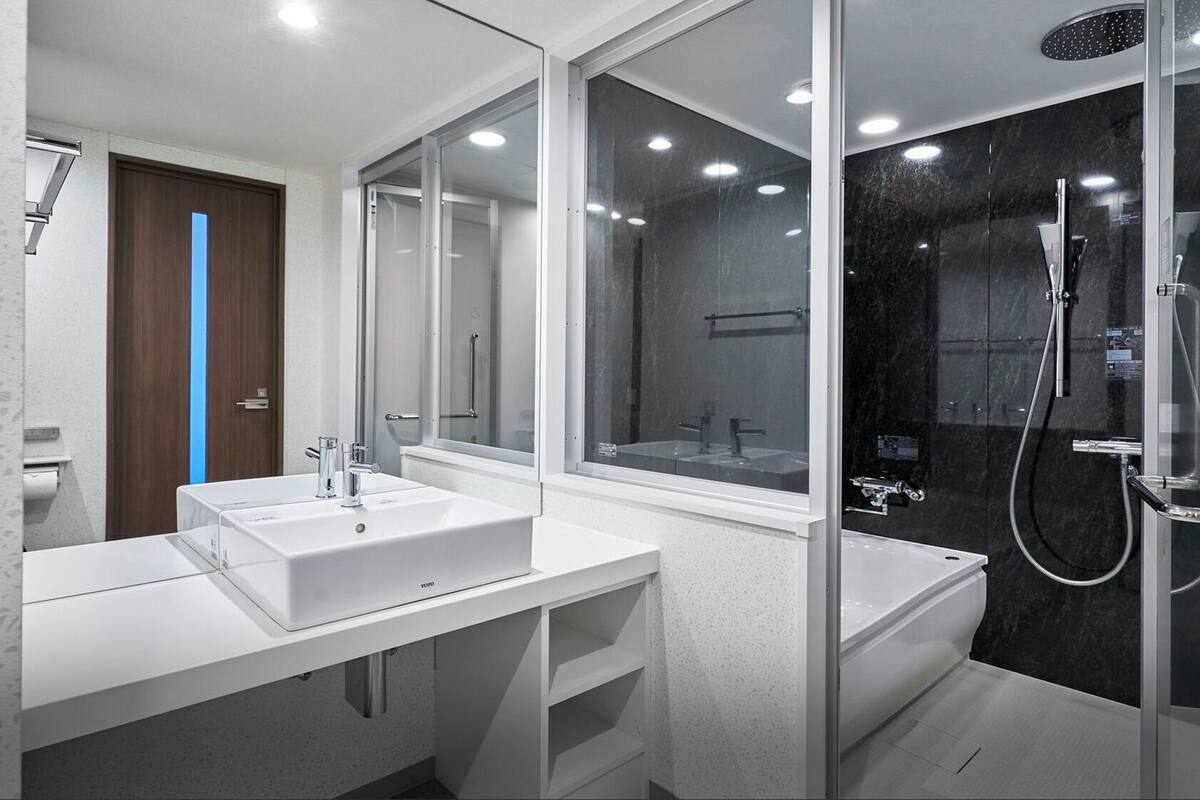 Een moderne badkamer met twee wasbakken, een douche en een grote spiegel.