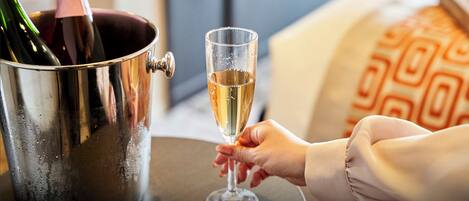 A hand holding a champagne flute next to a champagne bucket.