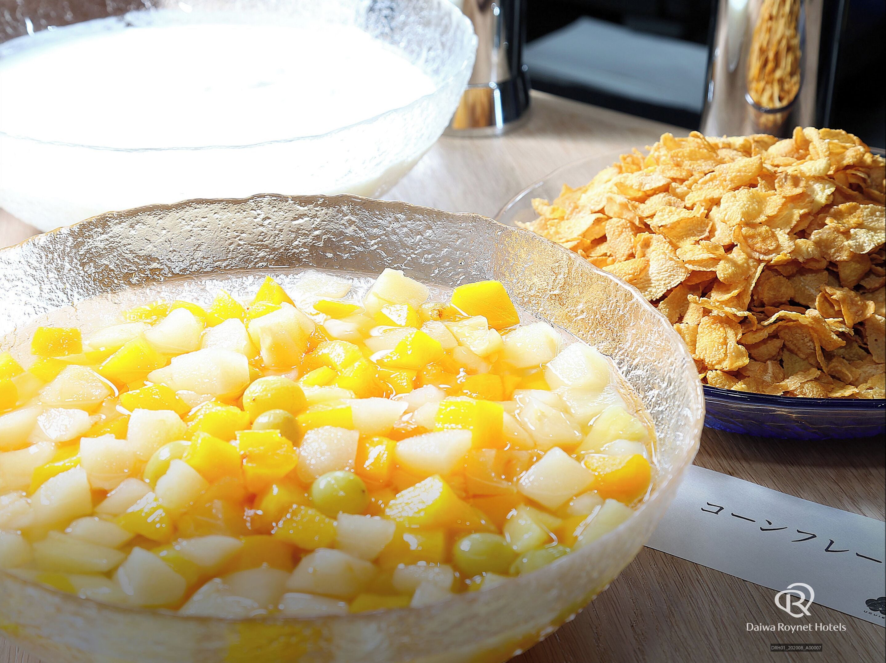 Una mesa con un cuenco de fruta picada, un cuenco de leche y un cuenco de papas fritas.