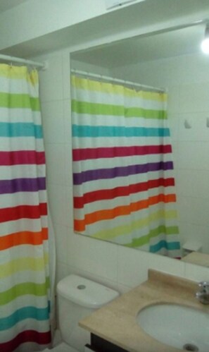 Un baño con cortina de ducha a rayas, un inodoro y un lavabo.