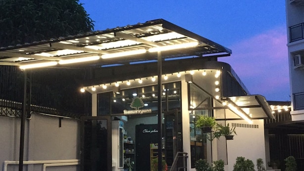 Un edificio moderno con un acceso cubierto, plantas en macetas y un cartel que dice "Chan Palace".