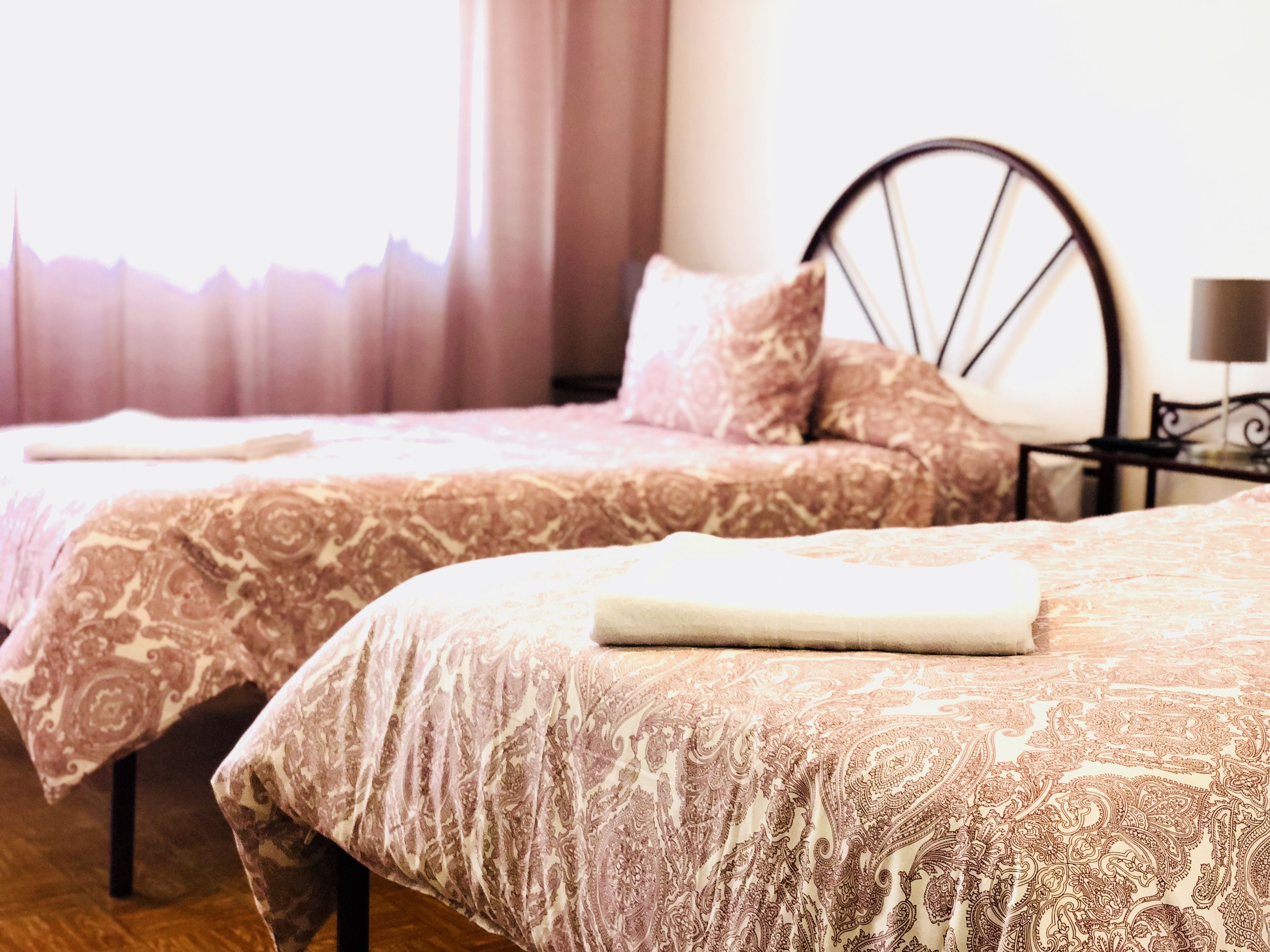 A hotel room with two beds, each with a patterned bedspread and pillows.