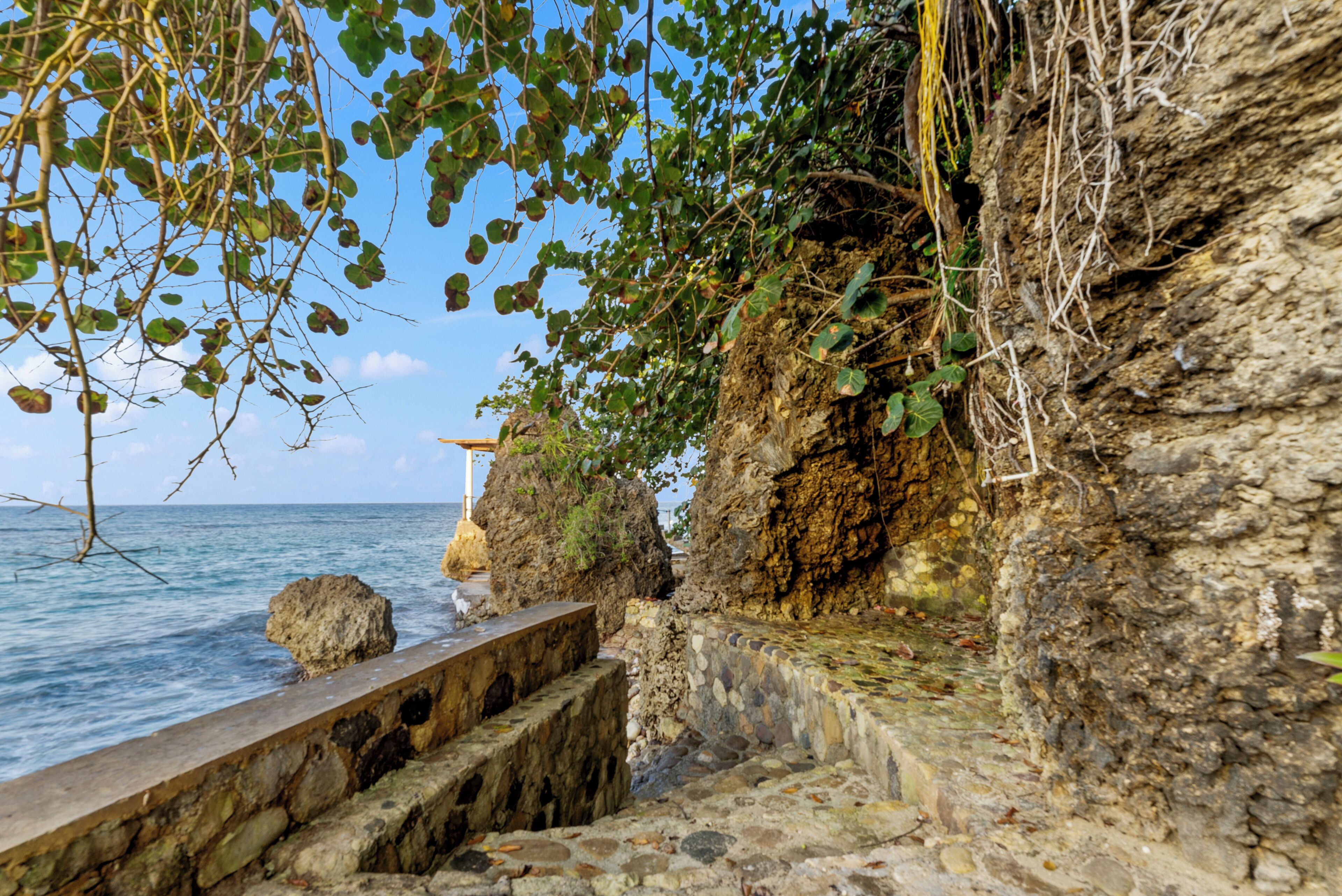 A coastal stone pathway leading to a rocky cliff overlooking the sea.