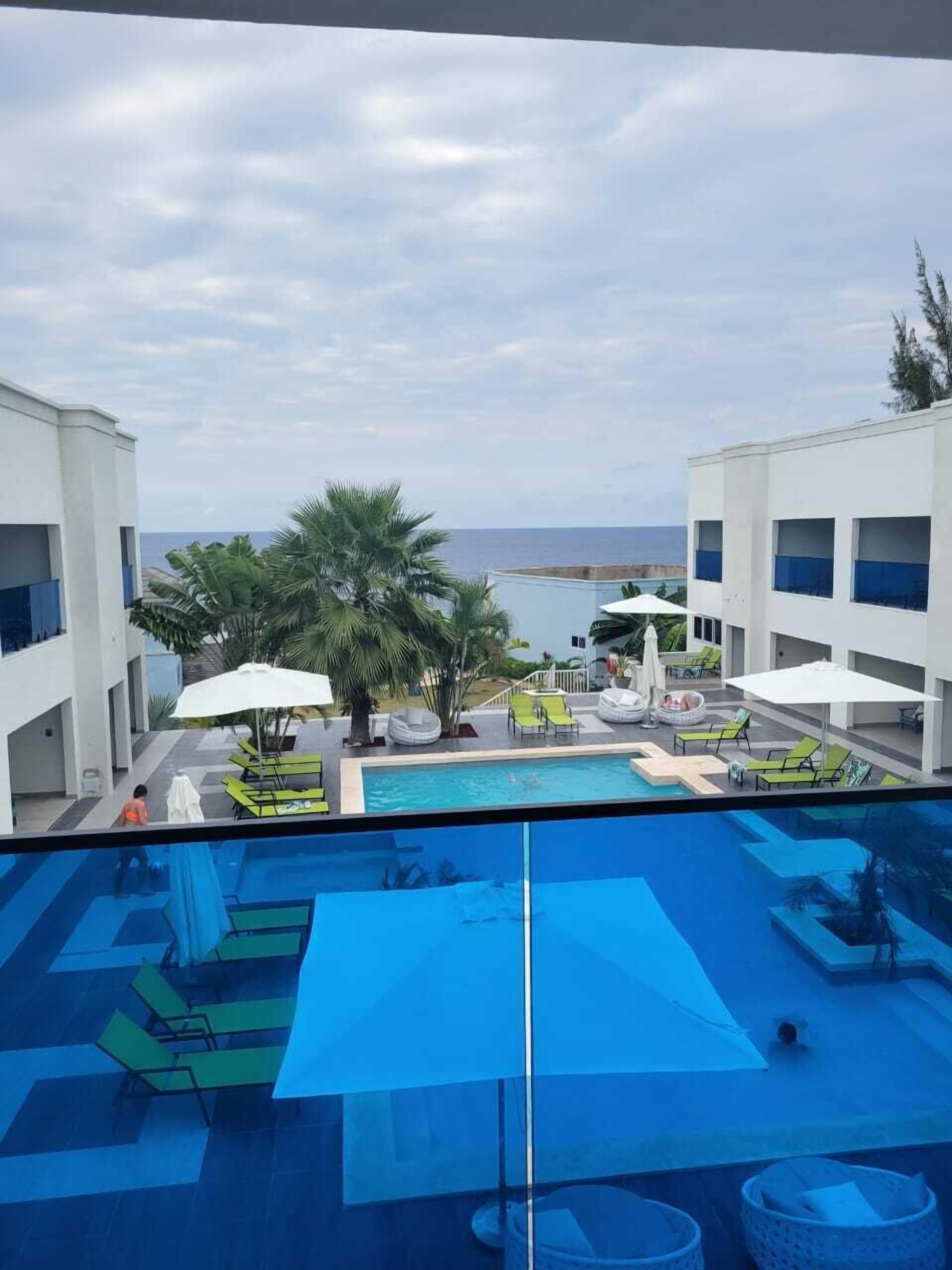 A pool area with lounge chairs and umbrellas, overlooking a body of water.