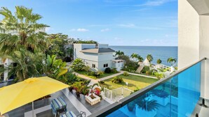 Una casa moderna con piscina, una sombrilla amarilla y vista al mar.