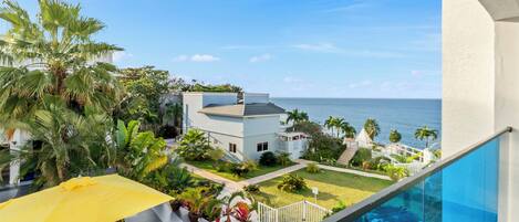 Ein modernes Haus mit Pool, einem gelben Sonnenschirm und Blick aufs Meer.