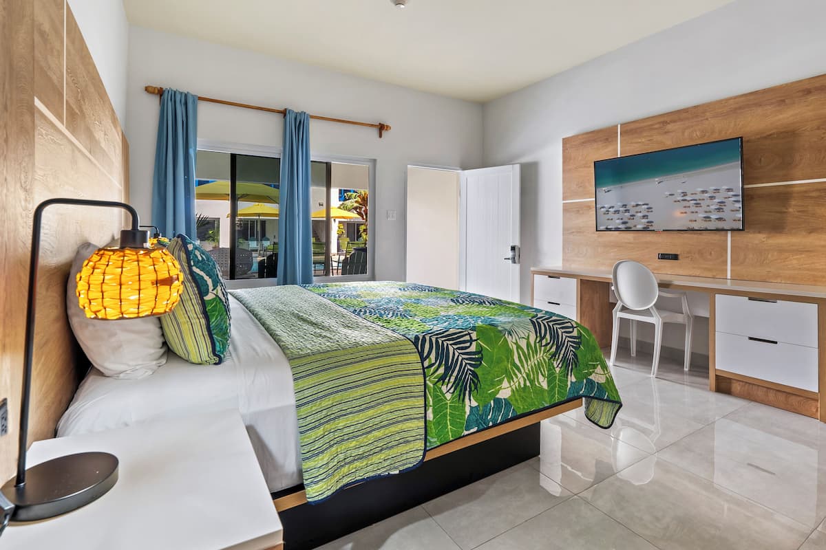 A modern bedroom with a bed, bedside lamp, and a view of the outdoors through a sliding door.