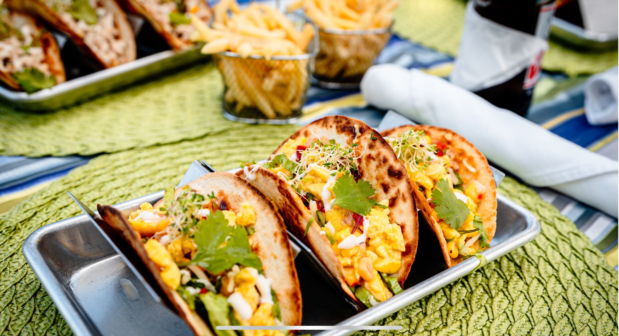 Tacos con guarniciones sobre una bandeja de metal.