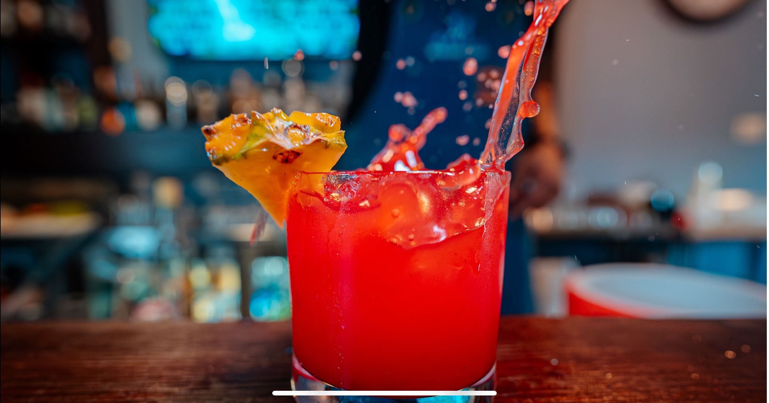 A cocktail with a slice of fruit garnish and ice cubes in a glass.