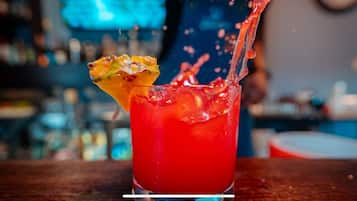 A cocktail with a slice of fruit garnish and ice cubes in a glass.