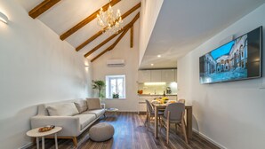 A modern living room with a sofa, coffee table, ottoman, dining table with chairs, and a chandelier. - Feel like an Emperor Apartment (Split)