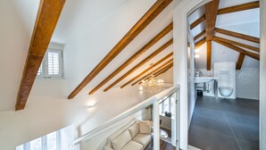 A spacious loft with exposed wooden beams, a modern kitchen, and a cozy seating area. - Feel like an Emperor Apartment (Split)