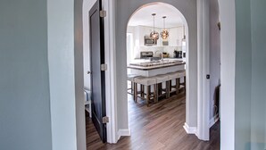 Una cocina moderna con una isla central, taburetes de bar e iluminación colgante.
